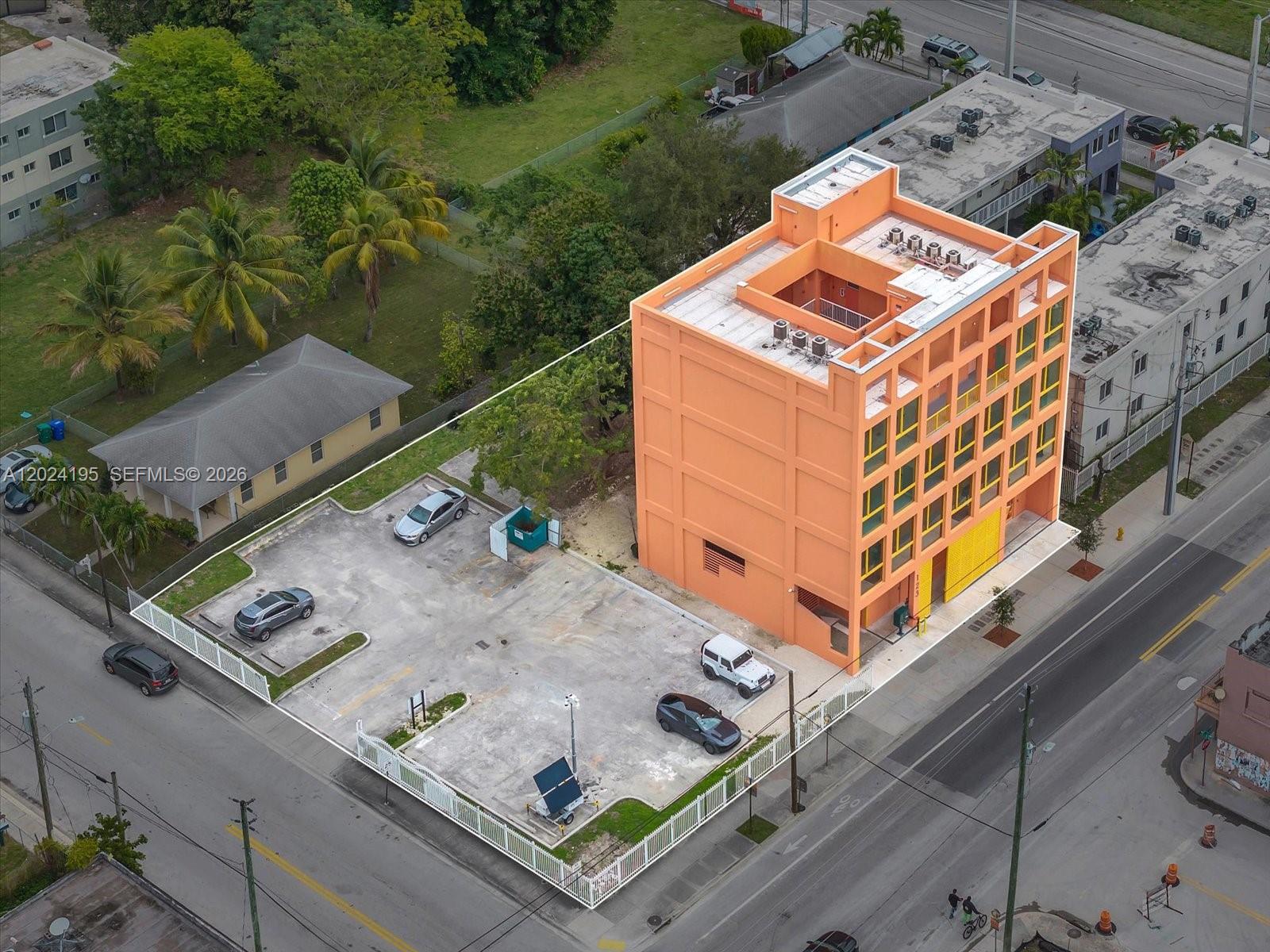 An aerial view shows a bright orange multi-story building with an adjacent paved parking lot — 123 NW 14th St # 201, Miami FL 33136, MIAMI, FL