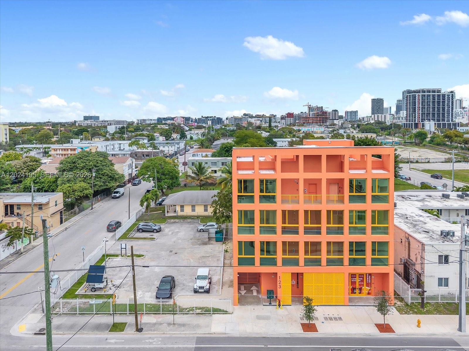An aerial view shows a bright orange, multi-story apartment building next to a parking lot — 123 NW 14th St # 201, Miami FL 33136, MIAMI, FL