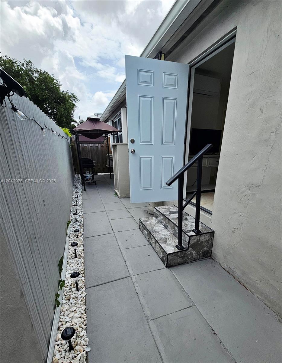 A paved side yard features a small set of stone-tiled steps leading to a doorway — 000 NW 51 AVE, Miami FL 33126, MIAMI, FL