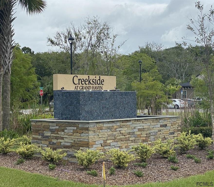 A stone monument sign for Creekside at Grand Haven stands in a landscaped garden area — 6 TEUNIS COURT, PALM COAST, FL
