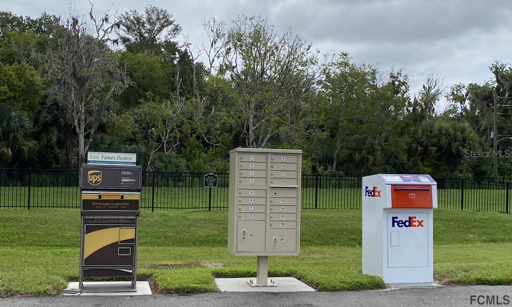 A row of mailboxes and shipping drop boxes stands on a concrete pad outdoors — 6 TEUNIS COURT, PALM COAST, FL