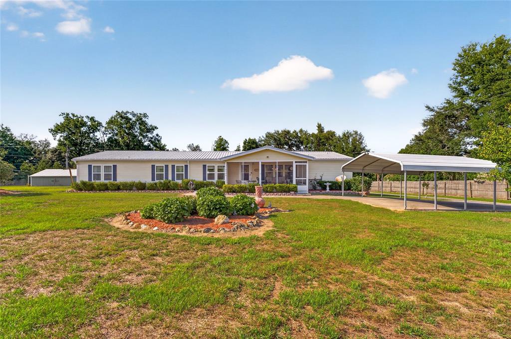 A single-story house with a screened porch and a detached metal carport — 9706 US HIGHWAY 301, DADE CITY, FL