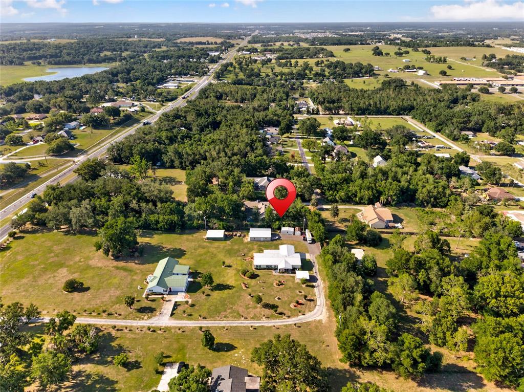 An aerial view shows a rural property with multiple buildings, trees, and a paved road — 9706 US HIGHWAY 301, DADE CITY, FL