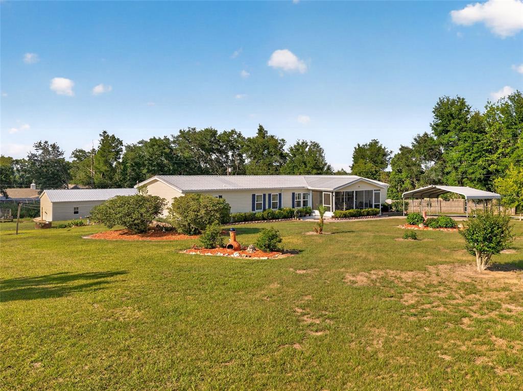 A single-story house with a metal roof, a detached garage, and a carport — 9706 US HIGHWAY 301, DADE CITY, FL