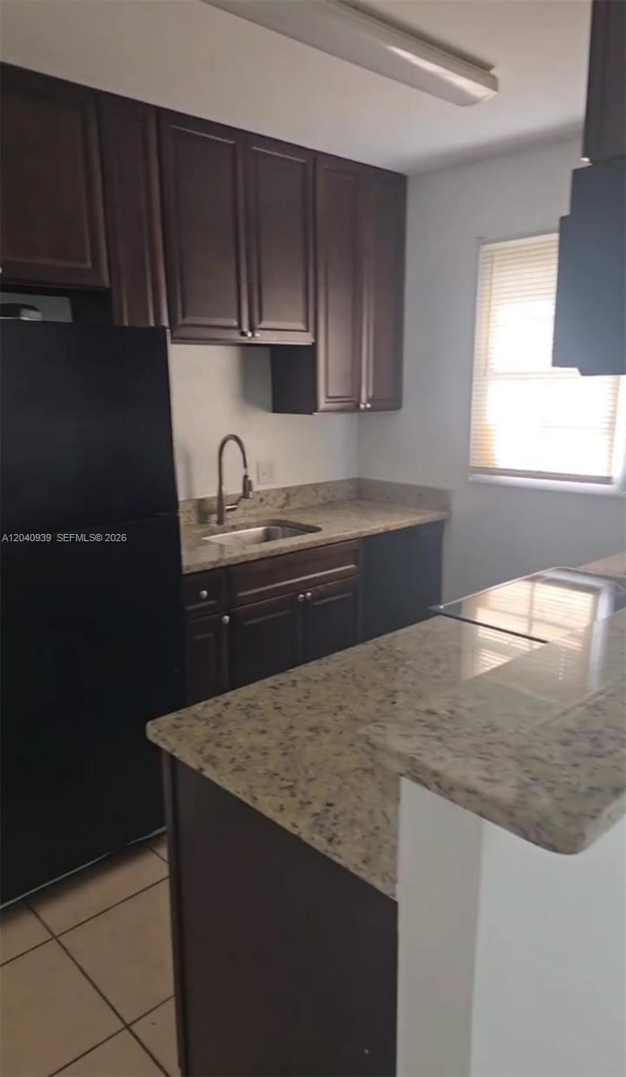 A kitchen features dark wood cabinets, granite countertops, and a black refrigerator — 2777 L B MCLEOD RD # C, Orlando FL 32805, ORLANDO, FL