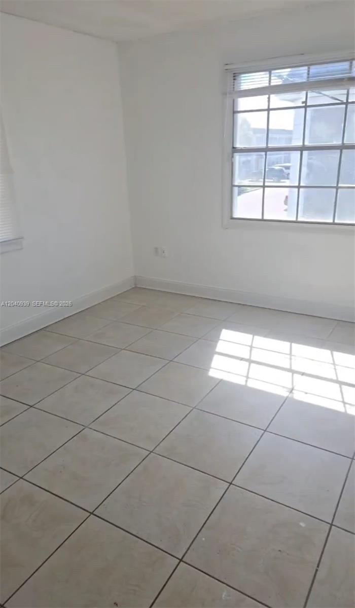An empty room features white walls, large square floor tiles, and a multi-pane window — 2777 L B MCLEOD RD # C, Orlando FL 32805, ORLANDO, FL