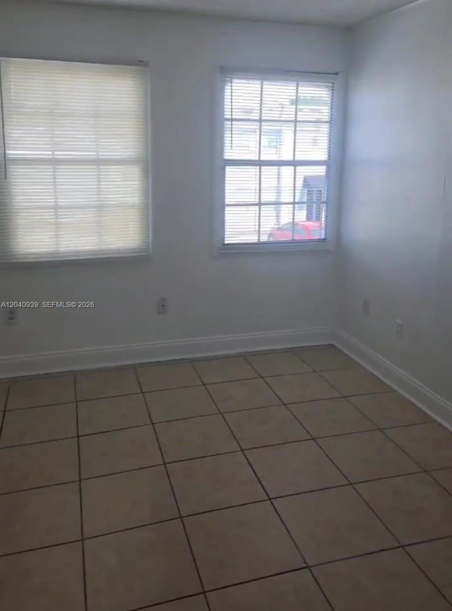 An empty room features white walls, tiled flooring, and two windows with closed blinds — 2777 L B MCLEOD RD # C, Orlando FL 32805, ORLANDO, FL