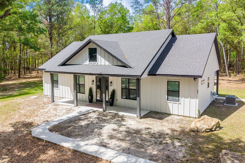 A white farmhouse-style home with a dark roof and a covered front porch — 456 SW BRADENTON WAY, FORT WHITE, FL