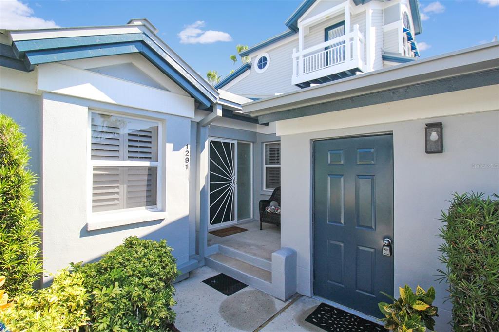The exterior of a house features a blue front door, a recessed entryway, and landscaping — 1291 SIESTA BAYSIDE DRIVE UNIT 1291A, SARASOTA, FL