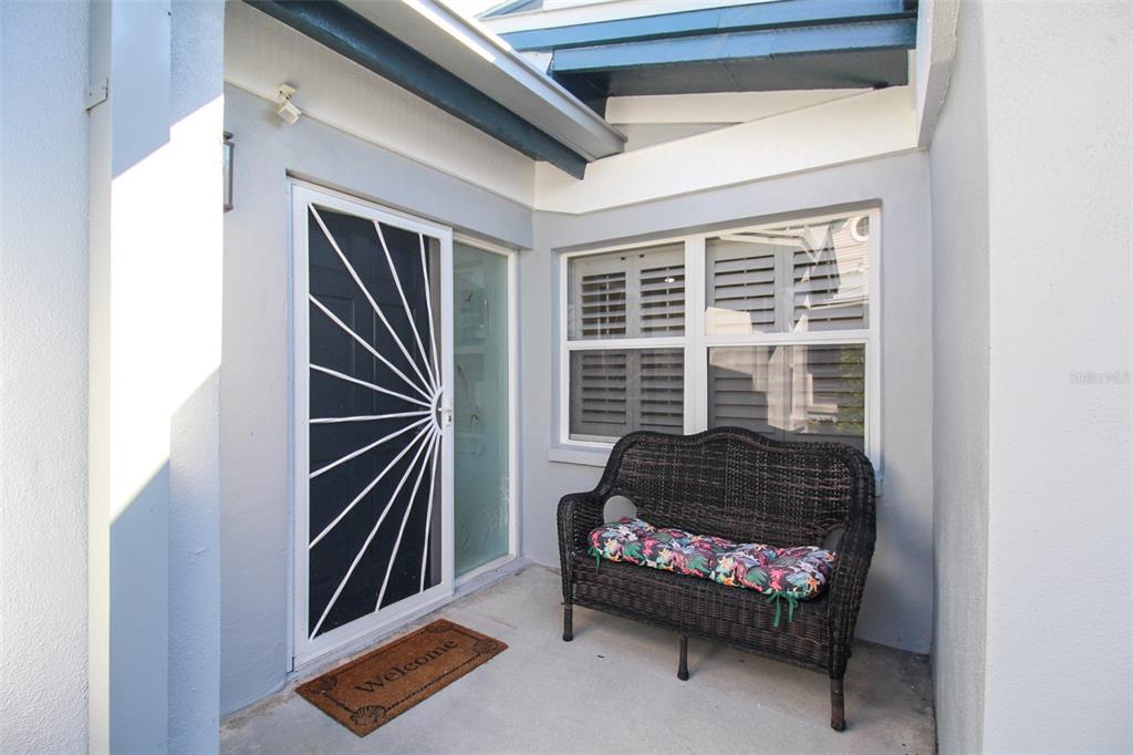 A covered entryway features a dark wicker bench, a screen door, and a welcome mat — 1291 SIESTA BAYSIDE DRIVE UNIT 1291A, SARASOTA, FL