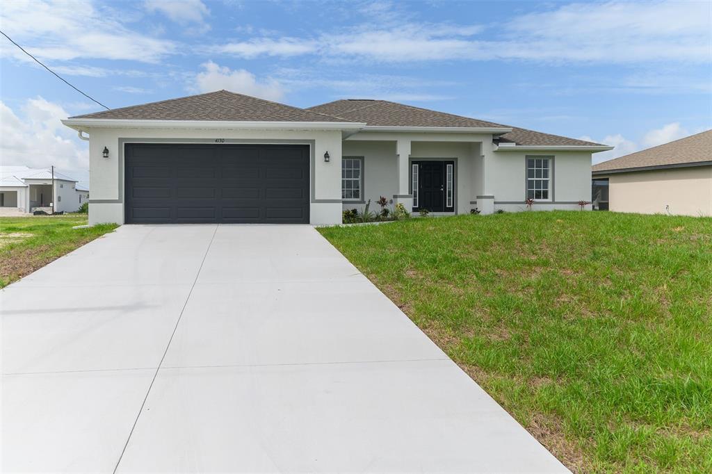 A single-story house with a gray garage door, white stucco exterior, and a concrete driveway — 4130 NW 33RD STREET, CAPE CORAL, FL