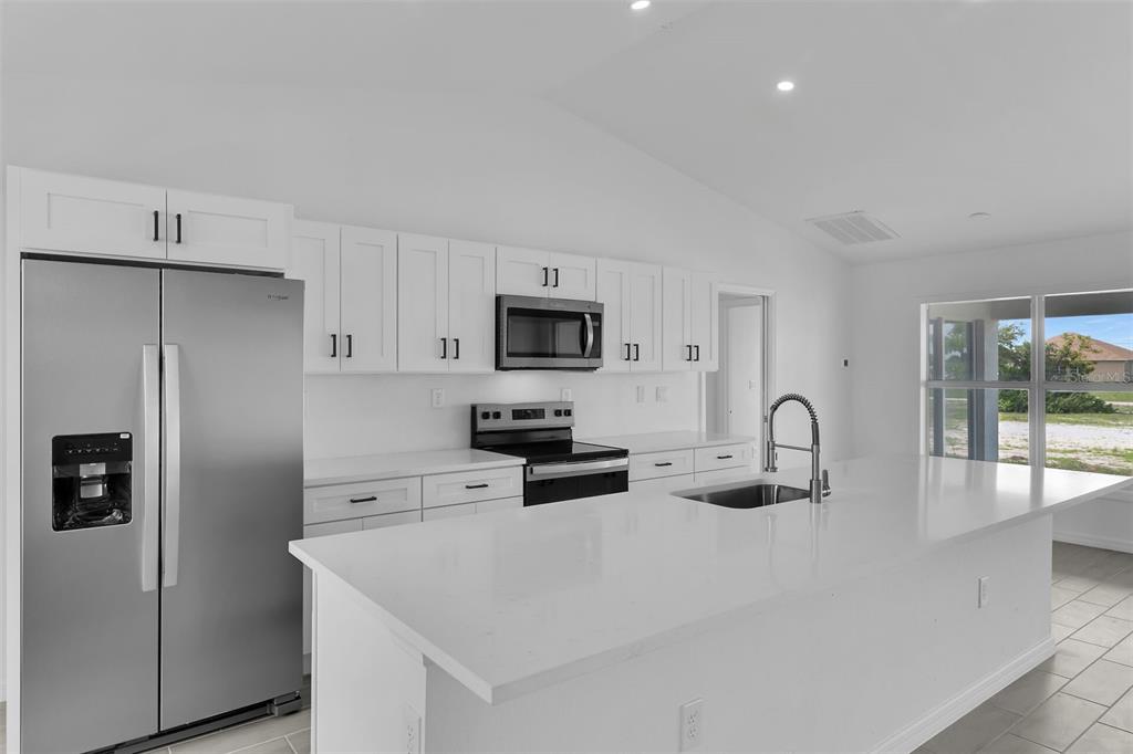 A modern kitchen features white cabinets, stainless steel appliances, and a large quartz island — 4130 NW 33RD STREET, CAPE CORAL, FL