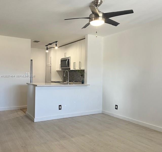 A kitchen with white cabinets and a breakfast bar opens into a living area — 10054 Winding Lake Rd # 201, Sunrise FL 33351, SUNRISE, FL