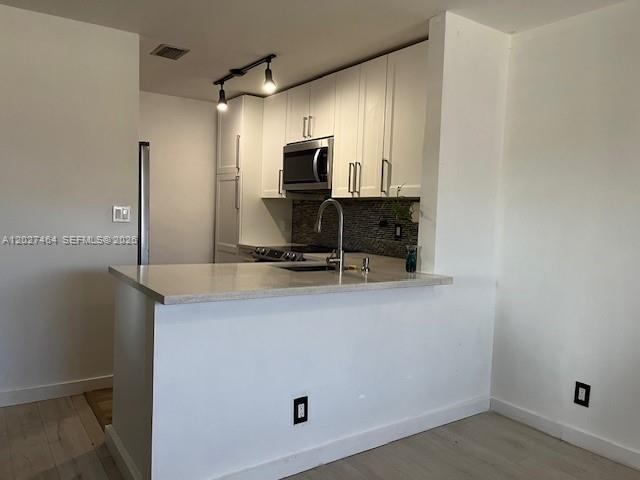 A kitchen features white cabinets, a stainless steel microwave, and a light-colored breakfast bar — 10054 Winding Lake Rd # 201, Sunrise FL 33351, SUNRISE, FL