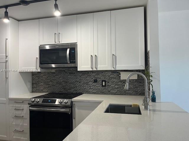 A modern kitchen features white cabinets, a stainless steel microwave, and a tiled backsplash — 10054 Winding Lake Rd # 201, Sunrise FL 33351, SUNRISE, FL