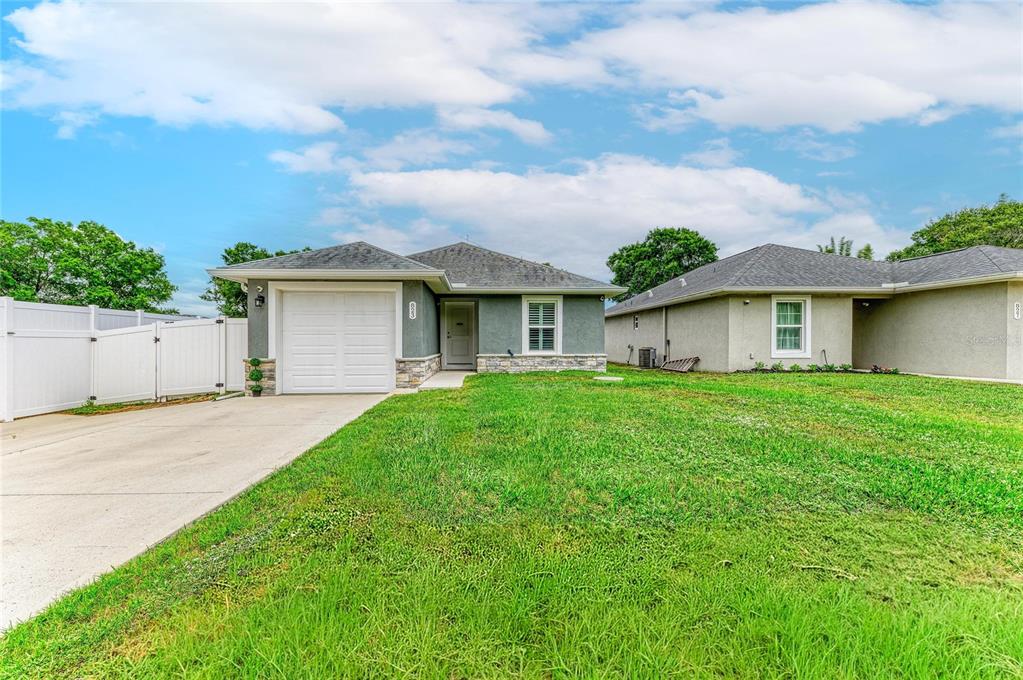 A single-story house with a gray stucco exterior, stone accents, and an attached garage — 823 BACON AVENUE, SARASOTA, FL