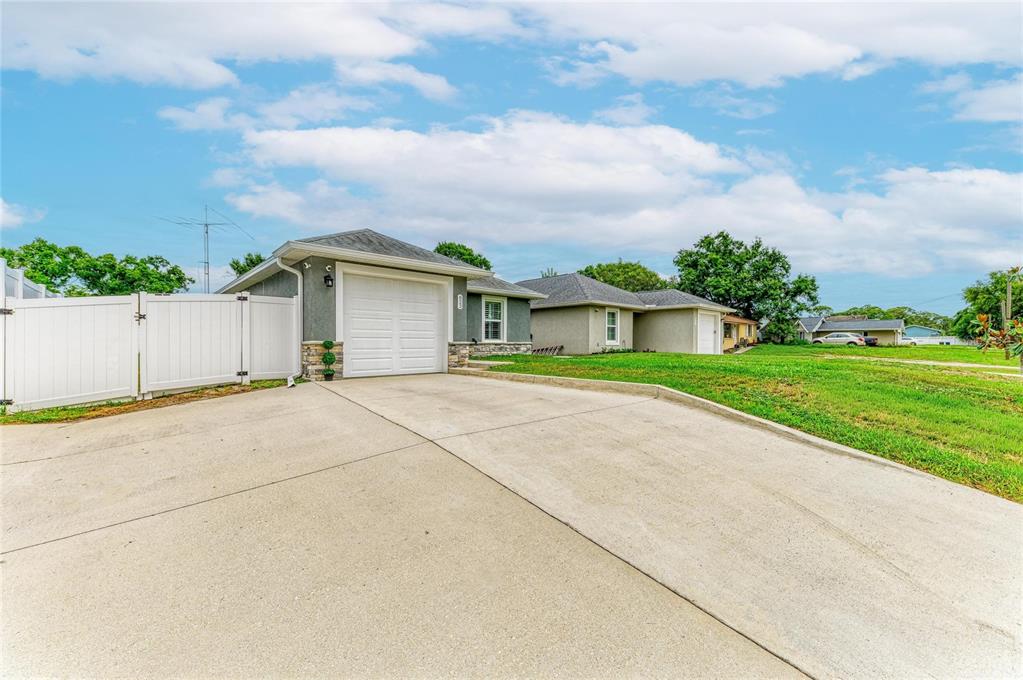 A single-story house with a one-car garage, concrete driveway, and white vinyl privacy fence — 823 BACON AVENUE, SARASOTA, FL