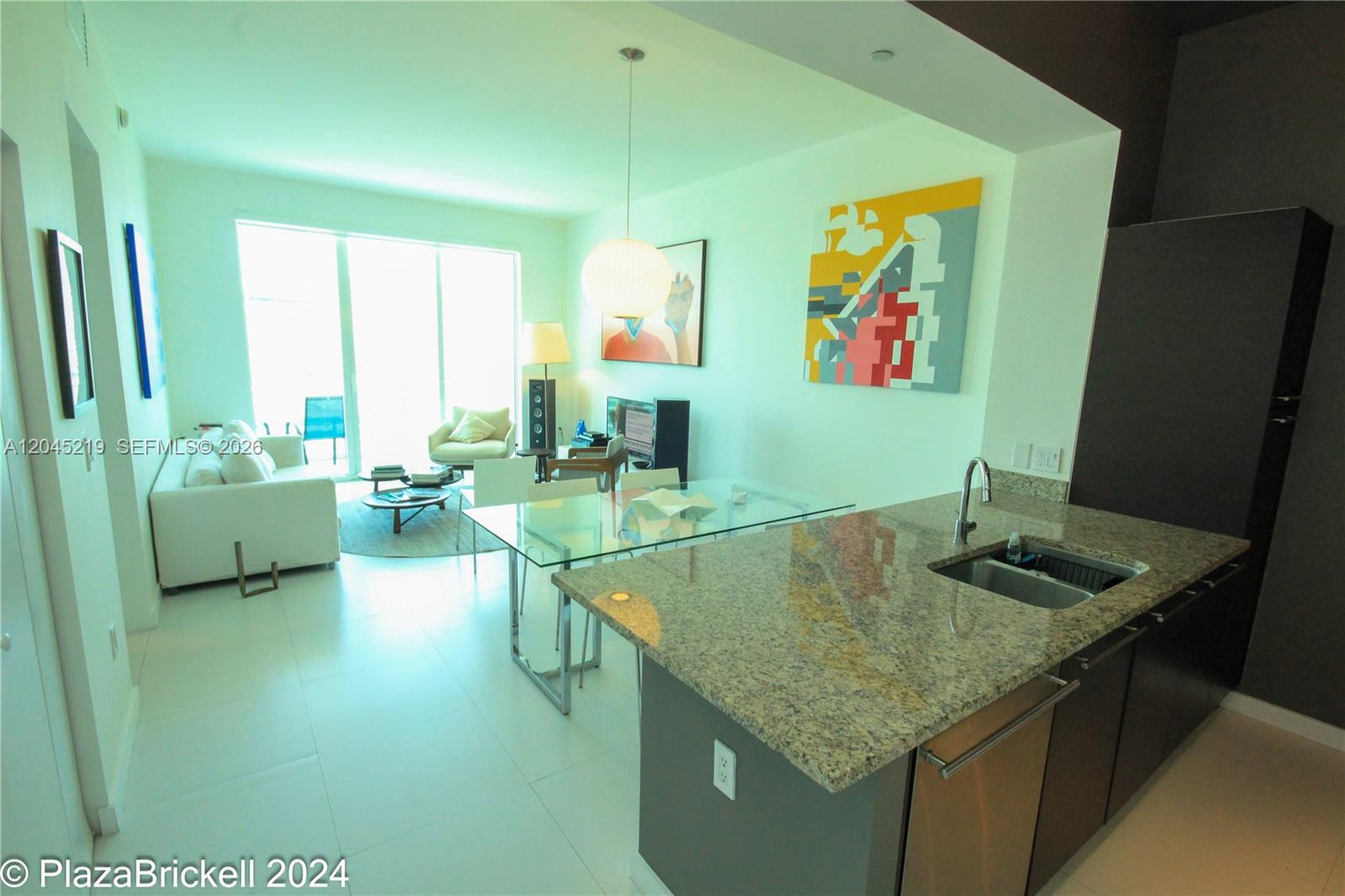 A modern apartment features an open kitchen with granite countertops and a living area — 950 Brickell Bay Dr # 5002, Miami FL 33131, MIAMI, FL