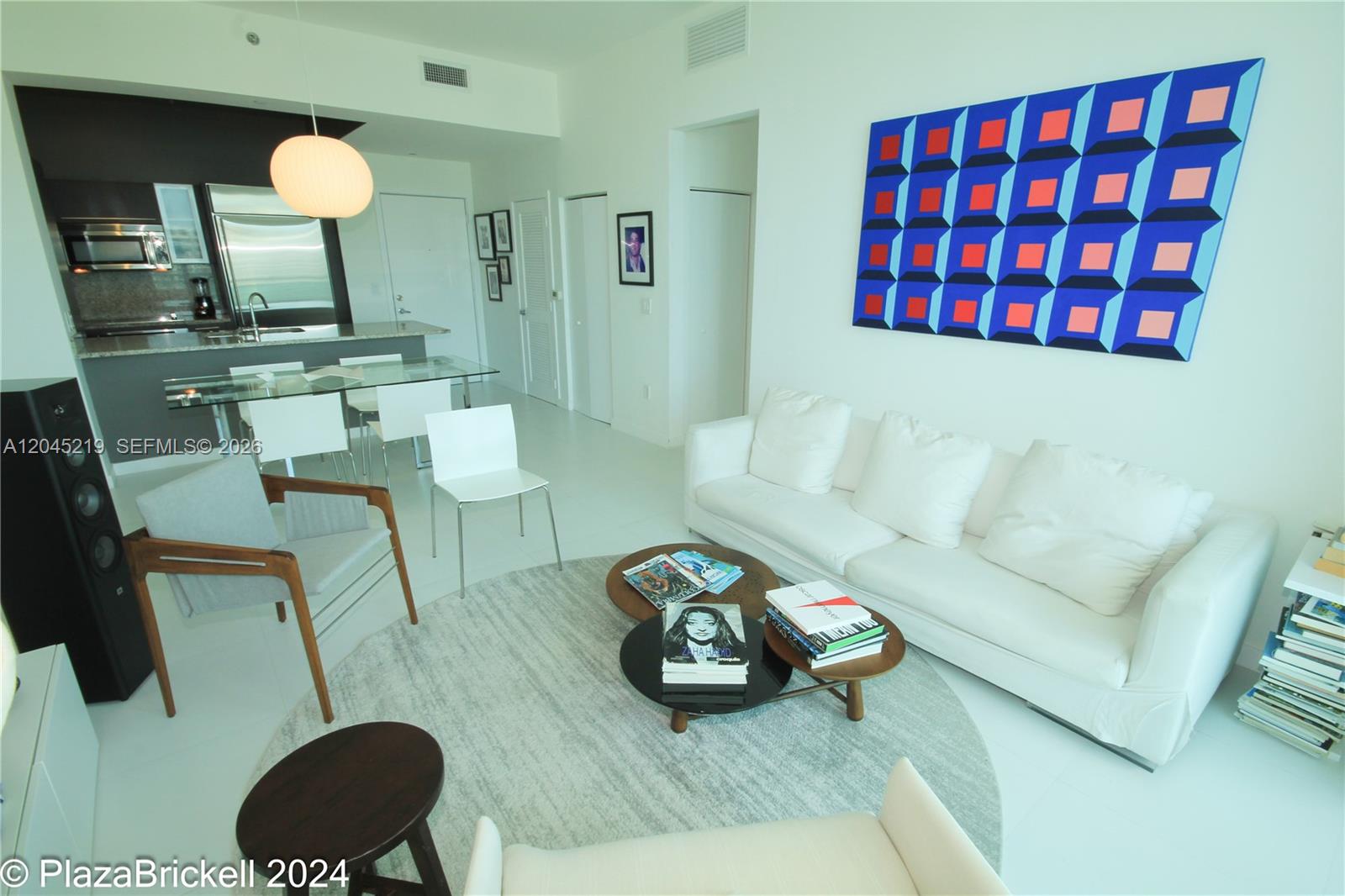 A modern living room features white furniture, a round rug, and a large geometric painting — 950 Brickell Bay Dr # 5002, Miami FL 33131, MIAMI, FL