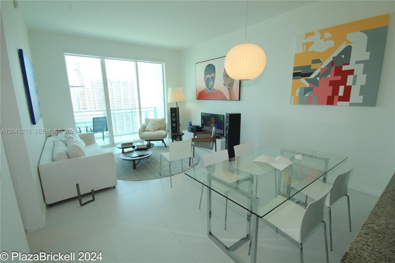 A modern living and dining area features white tile floors, glass furniture, and large windows — 950 Brickell Bay Dr # 5002, Miami FL 33131, MIAMI, FL