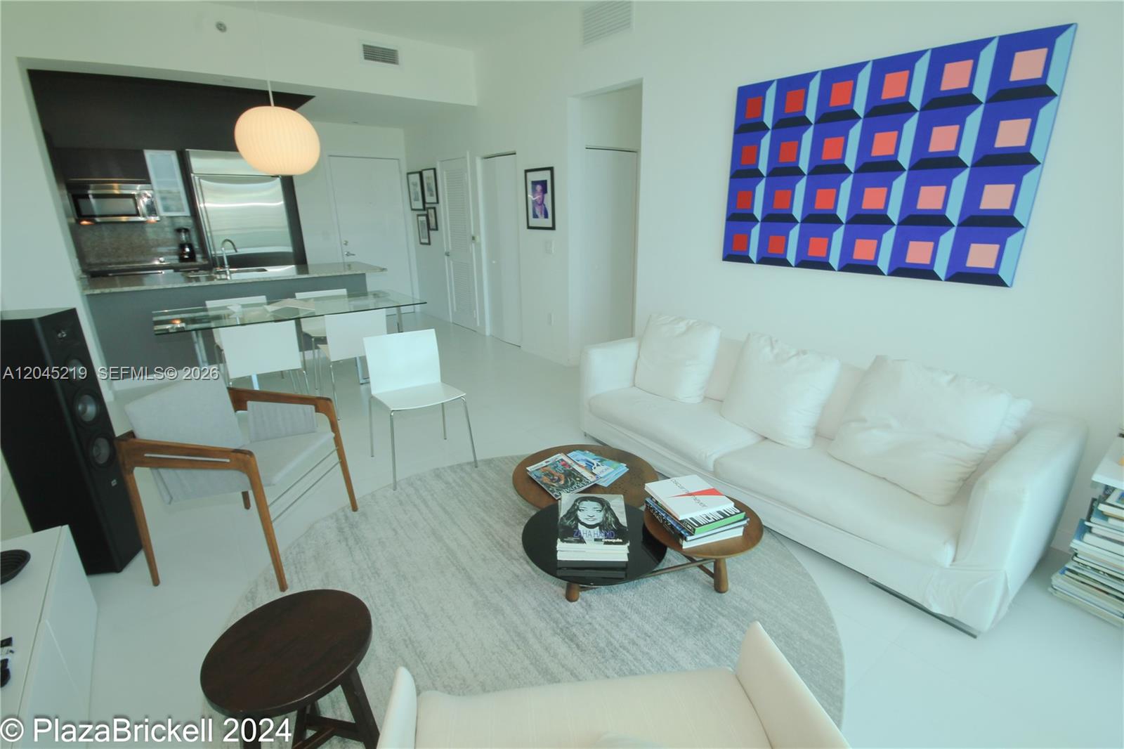 A bright living room features a white sofa, round coffee tables, and modern art — 950 Brickell Bay Dr # 5002, Miami FL 33131, MIAMI, FL