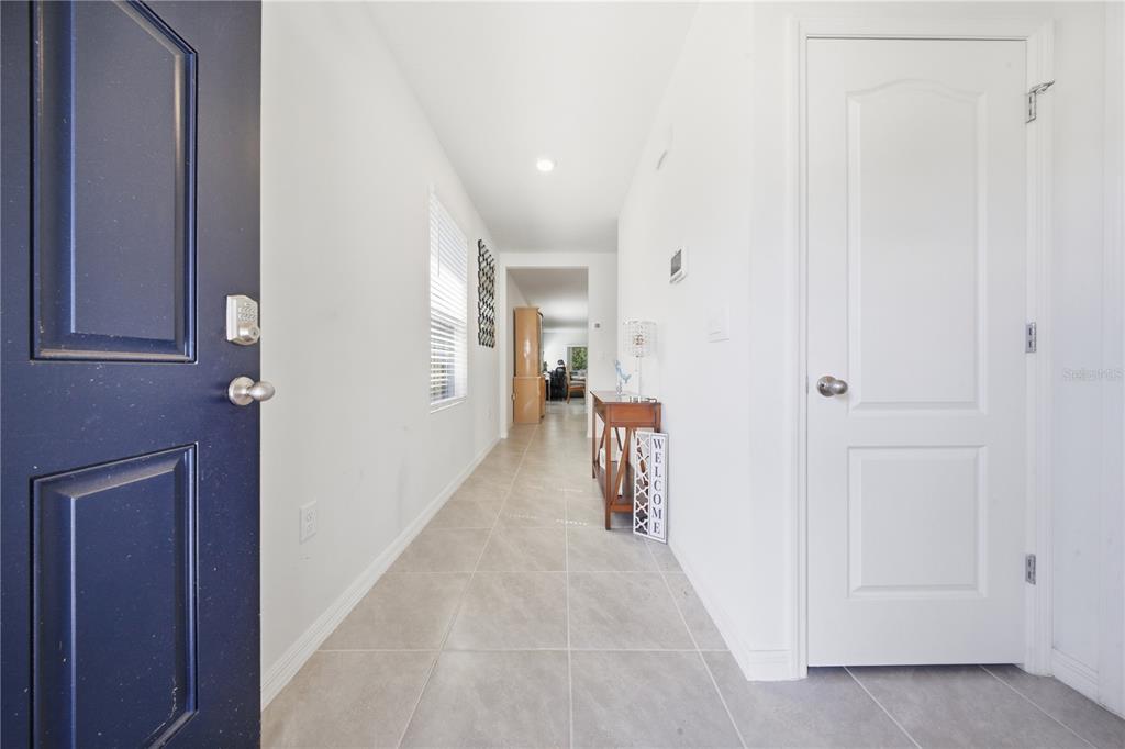 A bright entryway features a dark blue door, light tile flooring, and a white hallway — 479 PELHAM PARK DRIVE, DELAND, FL
