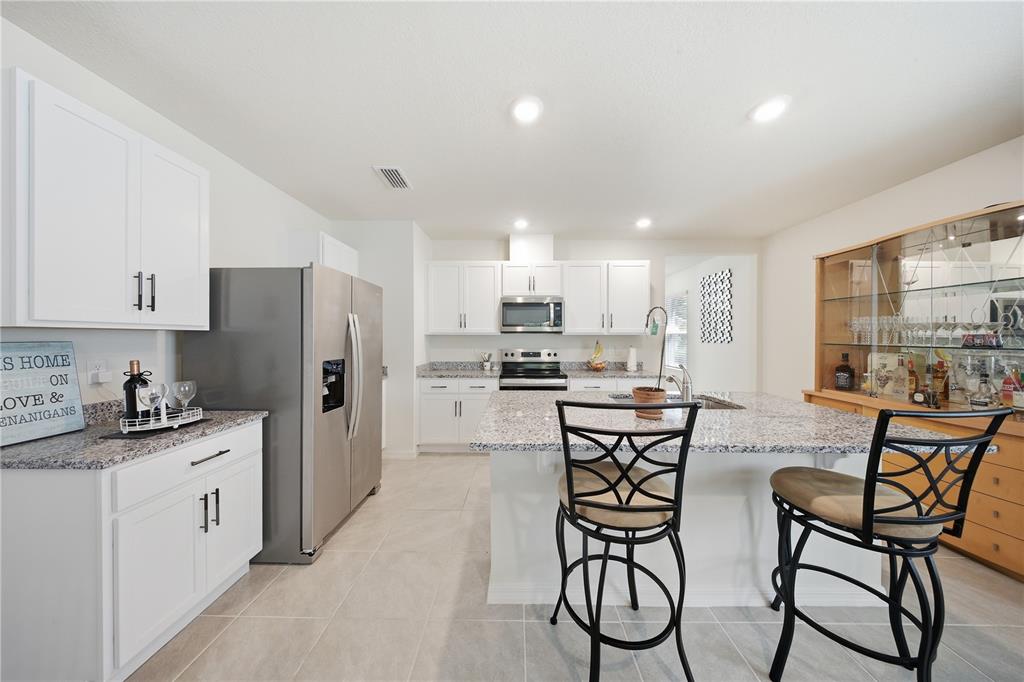 A kitchen features white cabinets, granite countertops, stainless steel appliances, and a central island — 479 PELHAM PARK DRIVE, DELAND, FL