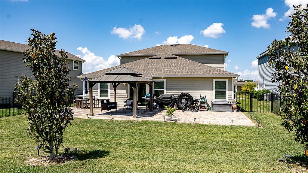 The backyard features a paved patio with a gazebo, lawn, and surrounding privacy fences — 5526 LIMESTONE STREET, MOUNT DORA, FL