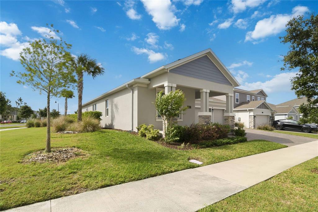 A single-story house with a covered porch, stone accents, and a driveway on a sunny day — 3000 ELLA WAY, ST CLOUD, FL