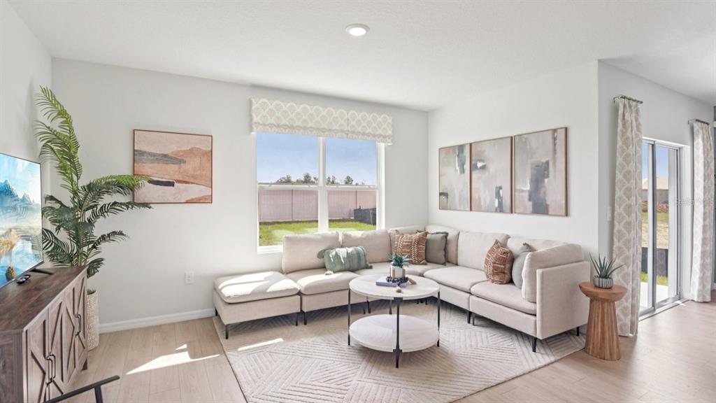 A living room features a beige sectional sofa, a round coffee table, and large windows — 8608 TIDEWATER TRAIL AVENUE, TEMPLE TERRACE, FL