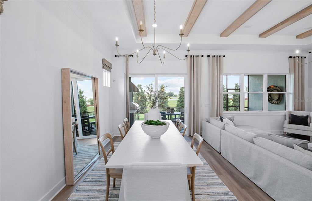 A dining room features a long white table, a chandelier, and a large floor mirror — 5764 SW 82ND TERRACE ROAD, OCALA, FL