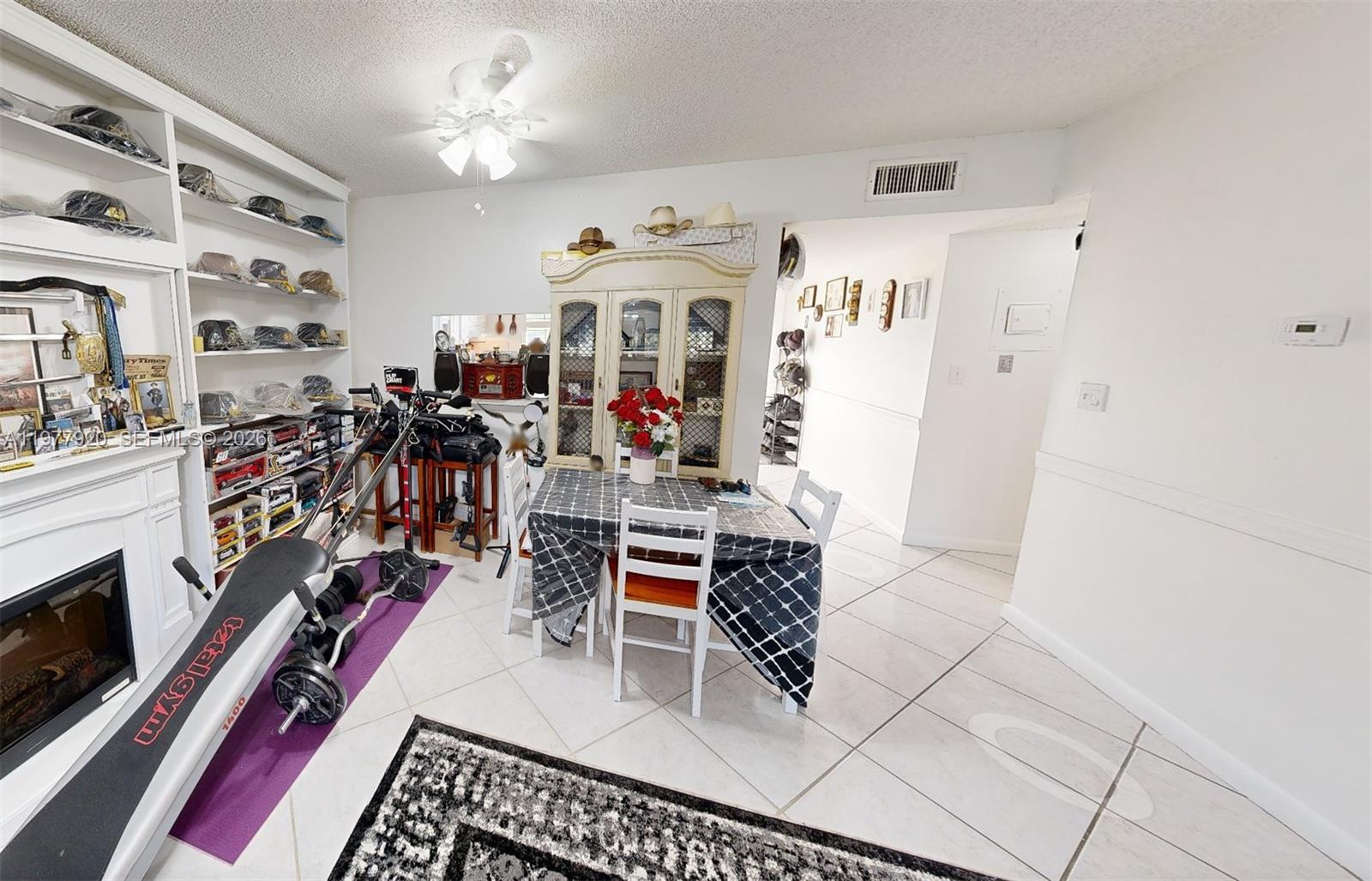 A dining area features a table with a patterned cloth, a hutch, and exercise equipment — 6570 Royal Palm Blvd # 215J, Margate FL 33063, MARGATE, FL