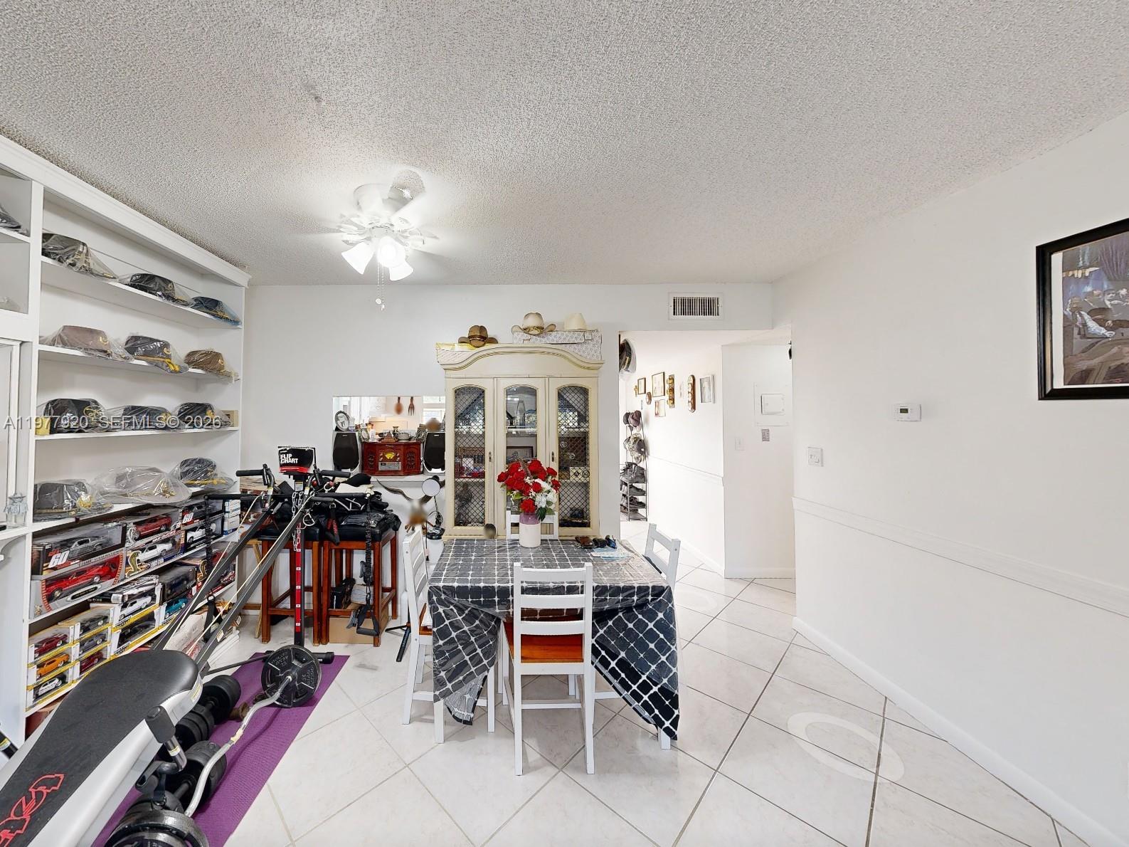 A dining area features a table, a display cabinet, and shelving filled with collectibles — 6570 Royal Palm Blvd # 215J, Margate FL 33063, MARGATE, FL