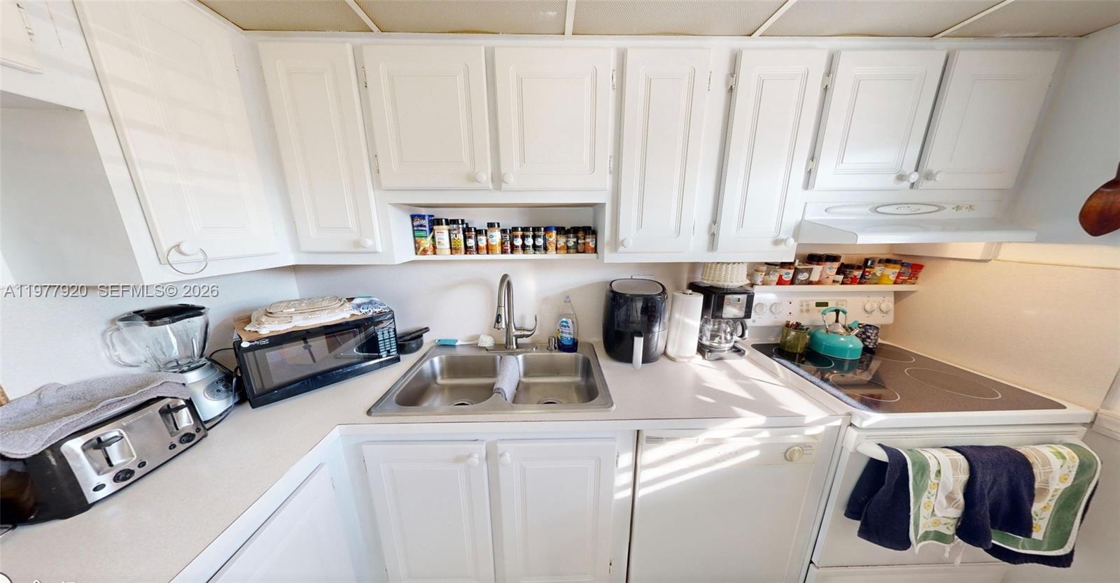 A kitchen features white cabinets, a double-basin sink, and a black electric stove — 6570 Royal Palm Blvd # 215J, Margate FL 33063, MARGATE, FL