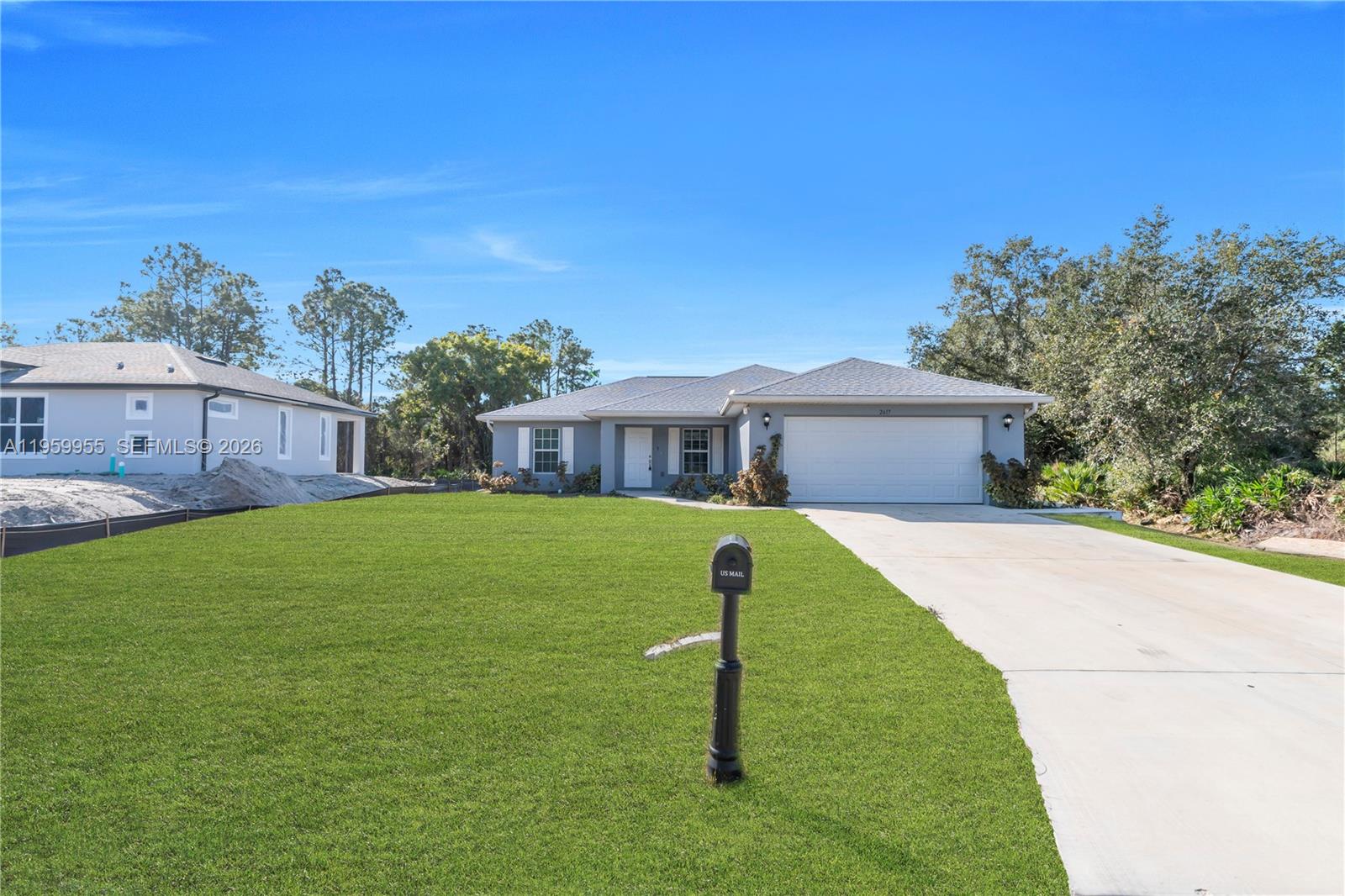 A single-story gray house with a white garage door and a large front lawn — 2617 53rd ST W, Lehigh Acres FL 33971, LEHIGH ACRES, FL