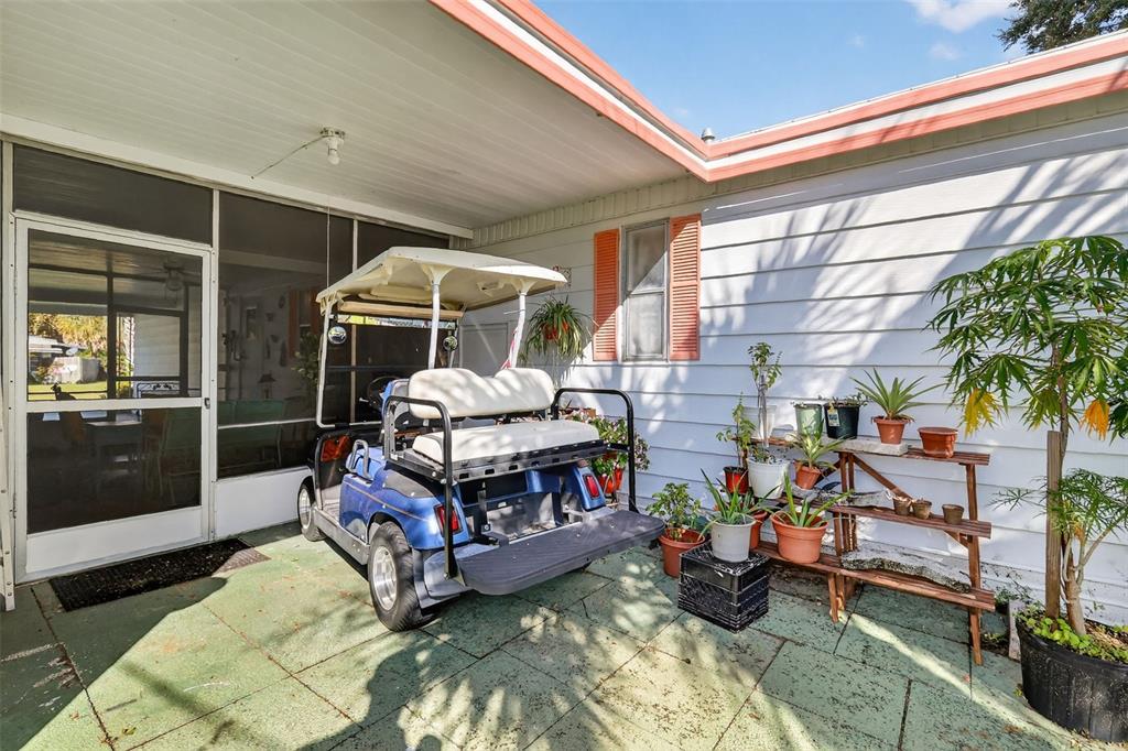 A blue golf cart sits on a concrete patio next to a house with siding — 11600 MAGNOLIA AVENUE, TAVARES, FL