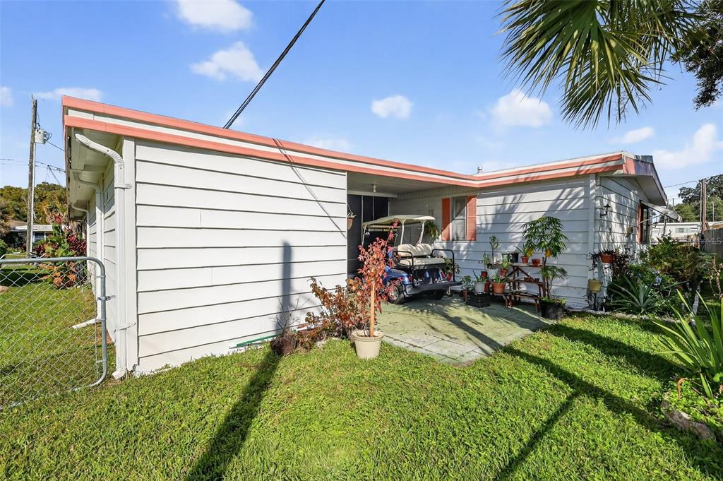The exterior of a white mobile home features a covered patio with a golf cart — 11600 MAGNOLIA AVENUE, TAVARES, FL