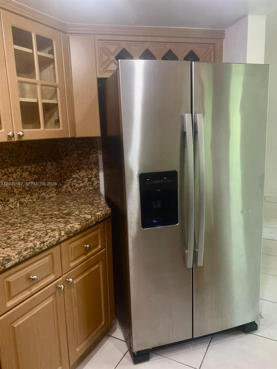 A stainless steel side-by-side refrigerator stands next to wood cabinets and granite countertops — 8305 SW 152nd Ave # 409, Miami FL 33193, MIAMI, FL
