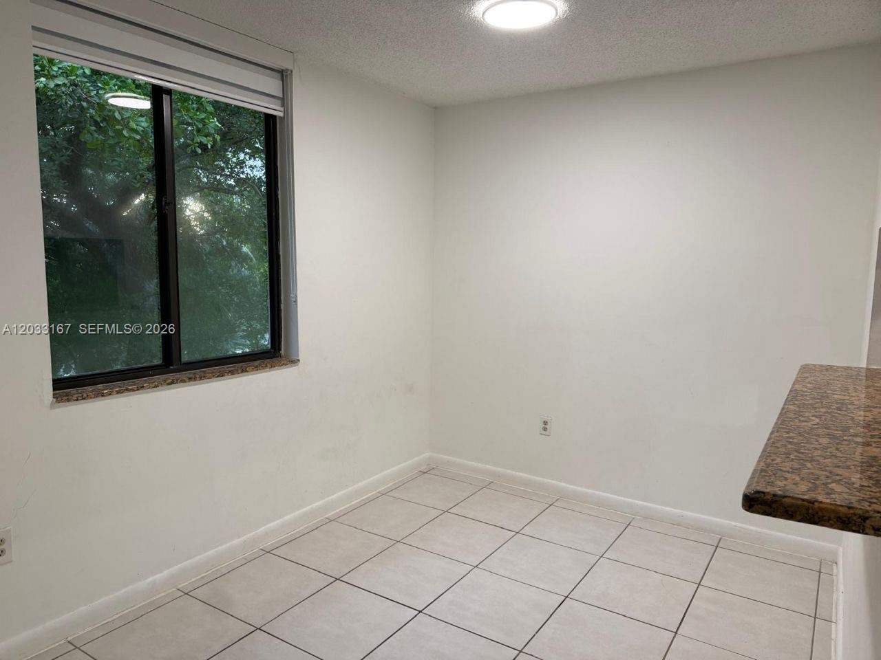 A small, empty room features white walls, light-colored floor tiles, and a large window — 8305 SW 152nd Ave # 409, Miami FL 33193, MIAMI, FL