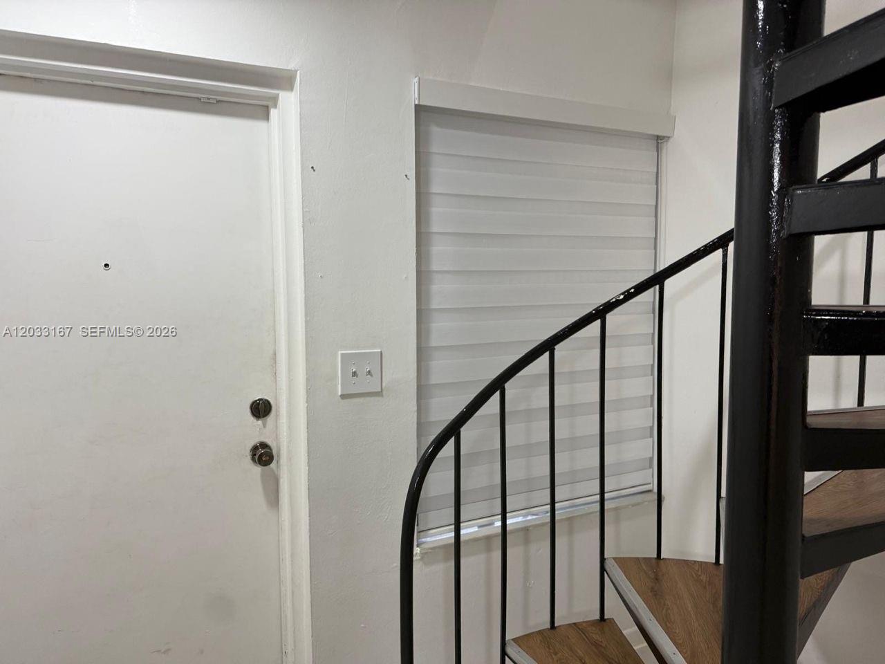 A white door stands next to a window with blinds and a black spiral staircase — 8305 SW 152nd Ave # 409, Miami FL 33193, MIAMI, FL