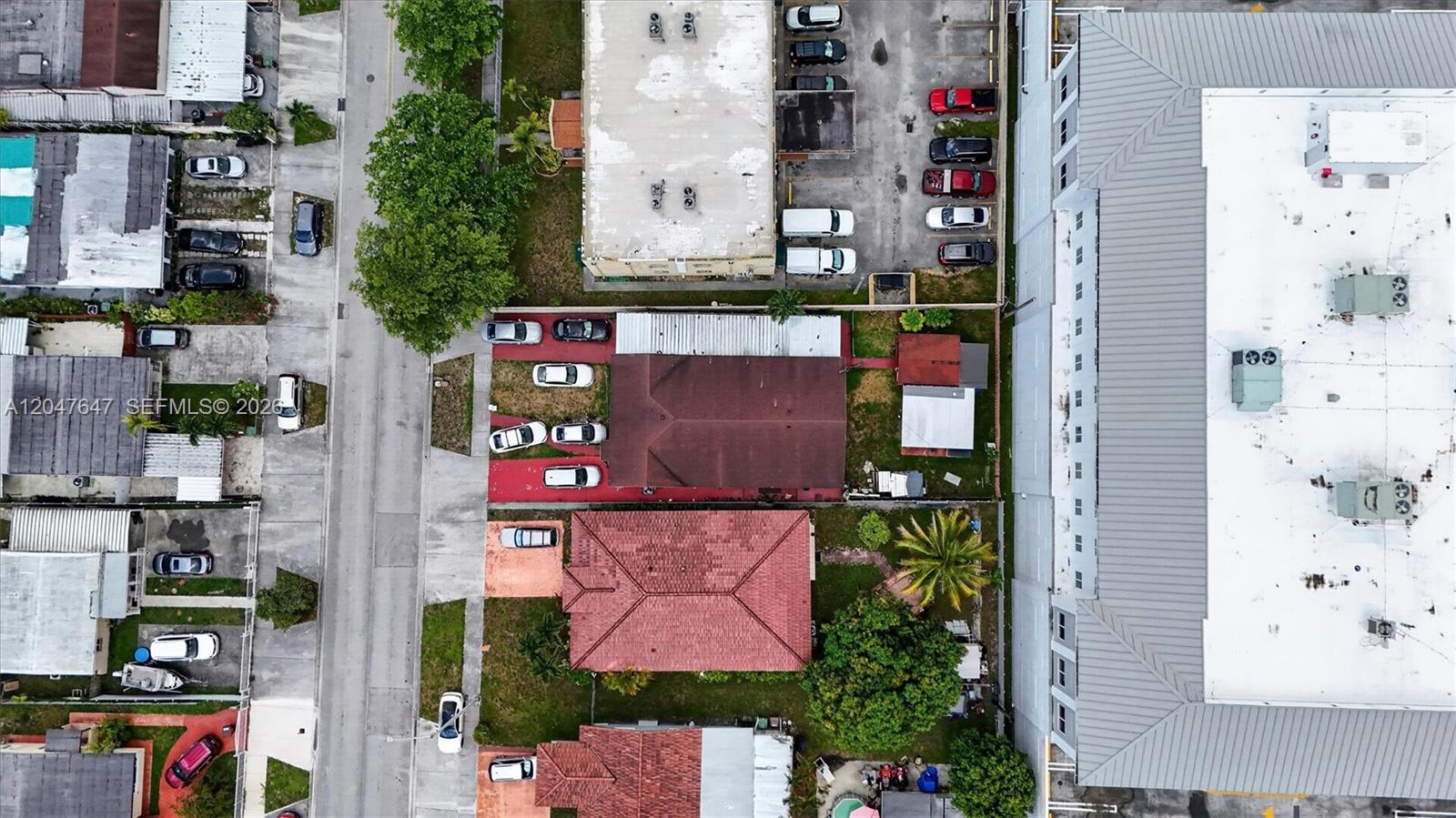 An aerial view shows several residential houses with red roofs and driveways along a street — 525 E 24th St, Hialeah FL 33013, HIALEAH, FL