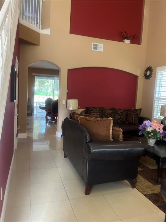 A living room with high ceilings, red accent walls, tile flooring, and a dark sofa — 4015 LAKESIDE RESERVE LANE, ORLANDO, FL