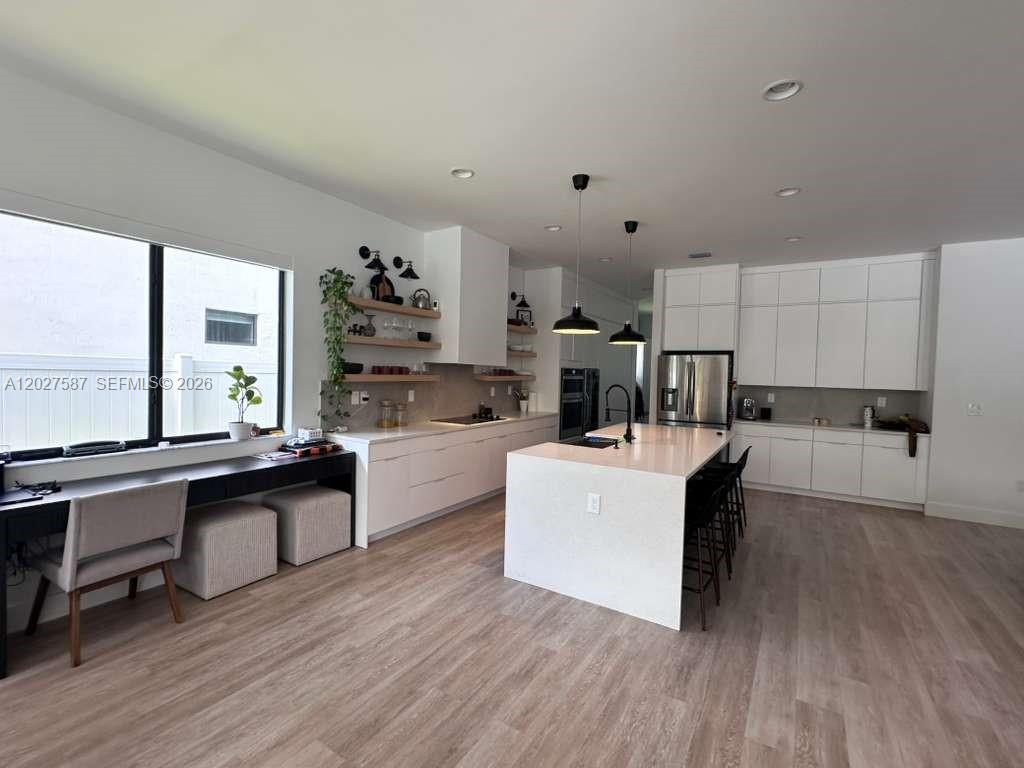 A modern kitchen features white cabinetry, a large central island, and a built-in desk area — 4572 SW 178th Ave, Miramar FL 33029, MIRAMAR, FL