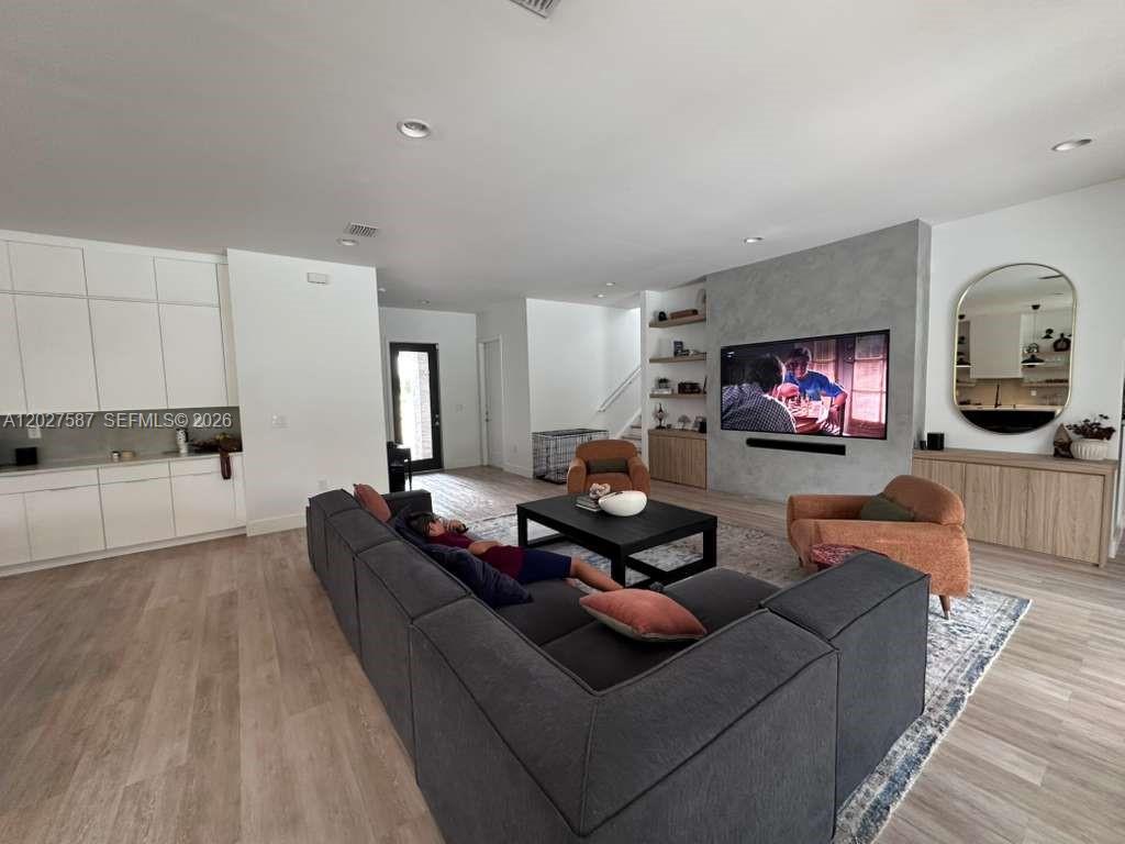 A modern living room features a large gray sectional, a concrete-textured accent wall, and wood cabinetry — 4572 SW 178th Ave, Miramar FL 33029, MIRAMAR, FL