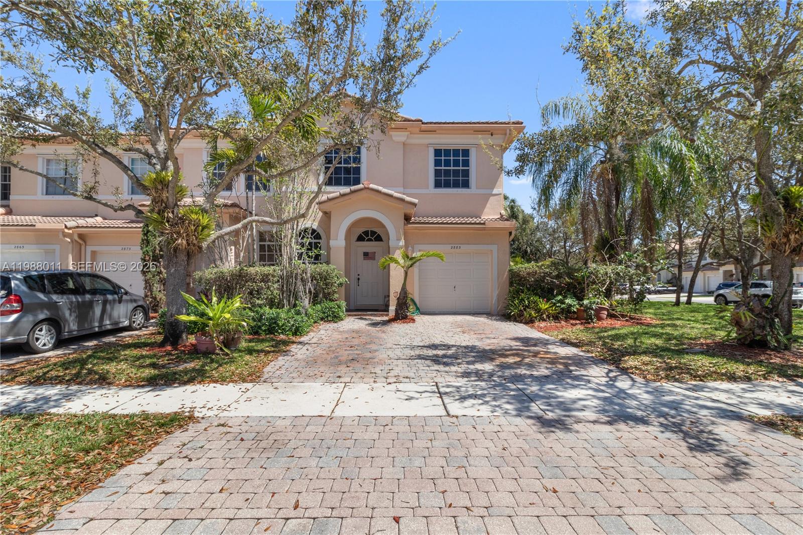 A two-story townhouse with a beige stucco exterior, a paved driveway, and a single-car garage — 2883 SW 85th Ave # 106, Miramar FL 33025, MIRAMAR, FL