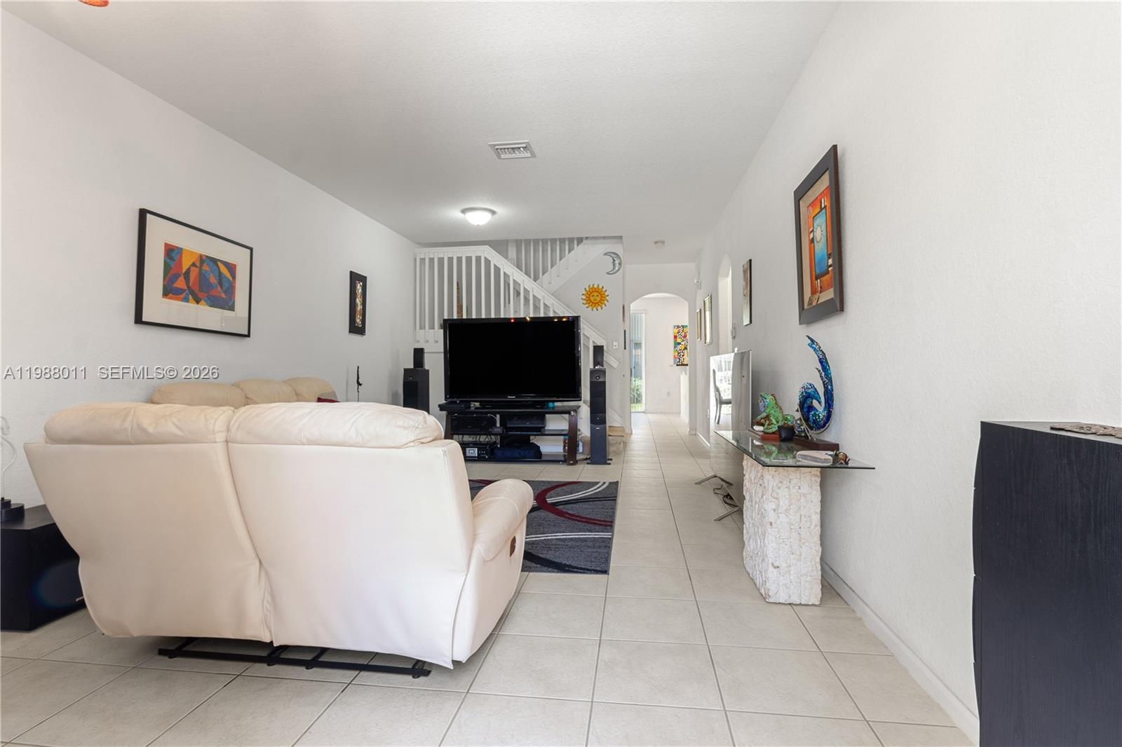A living room features white walls, tile flooring, a white sofa, and a television — 2883 SW 85th Ave # 106, Miramar FL 33025, MIRAMAR, FL