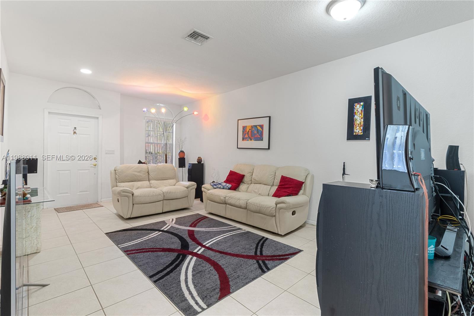 A living room features white tile floors, two cream-colored sofas, and a patterned area rug — 2883 SW 85th Ave # 106, Miramar FL 33025, MIRAMAR, FL