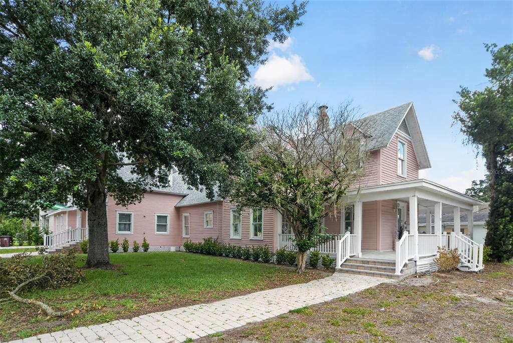 A two-story pink house with a white wraparound porch and a paved walkway — 19 W PRINCETON STREET, ORLANDO, FL