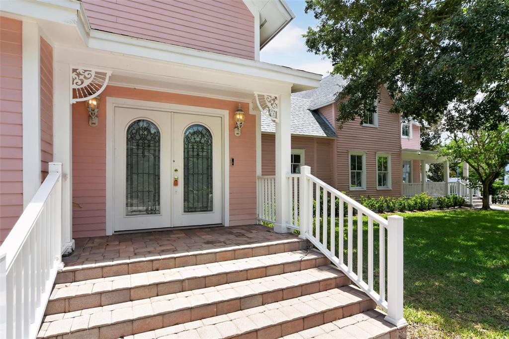 A pink house features a covered porch with stone steps and white railings — 19 W PRINCETON STREET, ORLANDO, FL