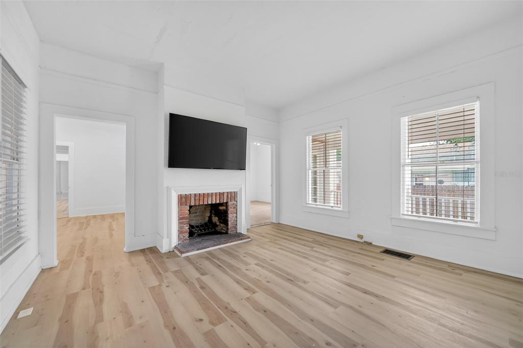 A living room features light wood flooring, white walls, a brick fireplace, and two windows — 19 W PRINCETON STREET, ORLANDO, FL